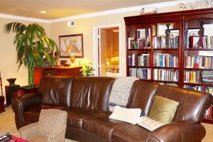 un sofá de cuero marrón en una sala de estar con estanterías en Shared Home, en Inglewood