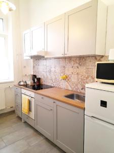 - une cuisine avec des placards blancs et un évier dans l'établissement D16 Apartman, à Szentgotthárd