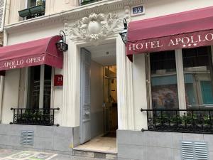 パリにあるHôtel Apollo Opéraの建物内の赤い日よけ2つ付きのホテル入口