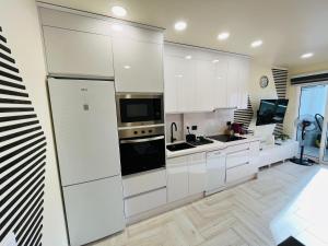 eine Küche mit weißen Schränken und einem großen Kühlschrank in der Unterkunft Atlantic Coast Apartment - Playa Del Inglés in Playa del Ingles