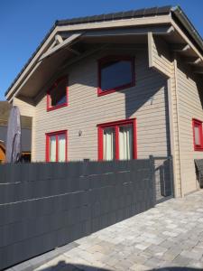 ein Haus mit roten Fenstern und einem schwarzen Zaun in der Unterkunft EifelGlückVII in Rieden