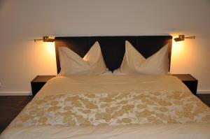 a bed with white pillows and a black headboard at Hotel Löwen in Mellingen