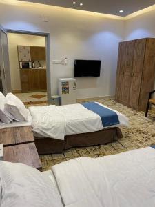 a hotel room with two beds and a flat screen tv at سويت روز العلا للشقق المفروشة sweet rose al ula organizing tours in AlUla