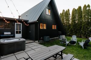 Casa negra con bañera de hidromasaje y mesa de picnic en Modern A-Frame with Hot Tub en Essexville