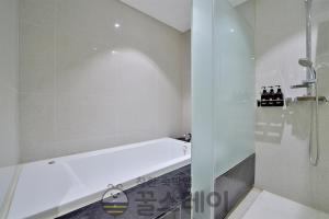 a white bathroom with a tub and a shower at Golden Hotel Incheon in Incheon