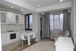 eine Küche mit weißen Schränken, einem Tisch und einer Couch in der Unterkunft Апартаменты в центре Бишкека in Bischkek