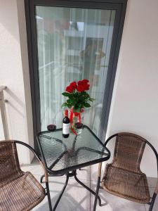 a glass table with a vase with red roses on it at Apartament Zamkowa Park Węgorzewo in Węgorzewo