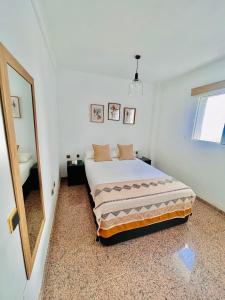 a white bedroom with a bed and a mirror at Encantadora Habitación Privada cerca del mar in Málaga