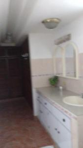 Baño blanco con lavabo y espejo en Hostal familiar Villa Nome en Penonomé