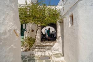 a woman walking down an alley in a white building at Little cellar in Chora Folegandros