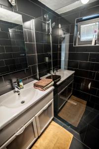 a black tiled bathroom with a sink and a mirror at Apartment Dolce Vita in Celje