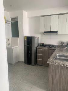 a kitchen with a black refrigerator and a sink at Aqualina Green Girardot in Girardot