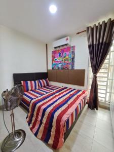 ein Schlafzimmer mit einem Bett mit einer bunten gestreiften Bettdecke in der Unterkunft Rayyan Ashraf homestay in Kota Bharu