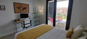 a bedroom with a bed and a desk with a television at Teatinos Suite in Málaga