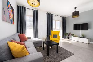 salon z kanapą i żółtym krzesłem w obiekcie Best Stay KRK w Krakowie