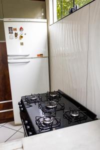 a stove top in a kitchen with a refrigerator at Guriri Recanto Paneágua cantinho de sossego in São Mateus