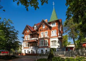 a large orange and white building with a green roof at Villa Neptun in Heringsdorf