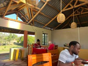 eine Gruppe von Menschen, die an einem Tisch in einem Restaurant sitzen in der Unterkunft Masai Heritage Guesthouse in Ololaimutiek