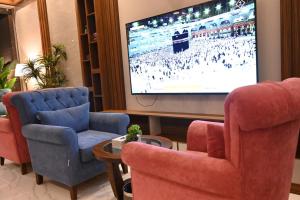 sala de estar con 2 sillas y TV de pantalla plana en جوهرة السراة للأجنحة الفندقية, en Khamis Mushayt