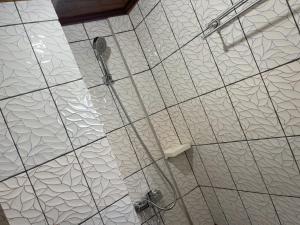 y baño con ducha y techo de azulejos blancos. en Complexe Meublé PEPON, en Douala