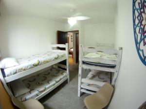 a room with two bunk beds and a chair at Apartamento Dona Frida Prainha com WiFi pé na areia in Caraguatatuba