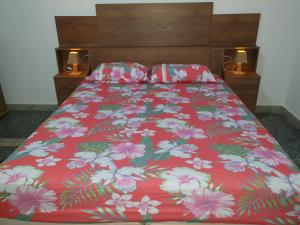 uma cama com um cobertor vermelho com flores em Casa Verde em Limeira