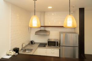 a kitchen with a stainless steel refrigerator and two lights at Hotel Casa Hemingway in Juan Dolio