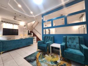 a living room with two blue chairs and a tv at Solok Burma Vacation Home @ Gurney Penang in George Town