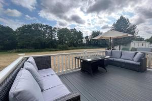 a deck with couches and a table and an umbrella at Foxglove 10 in Ringwood