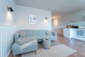 ein Wohnzimmer mit einem blauen Sofa und einer Küche in der Unterkunft Strandkoje Wohnung 7 in Rettin