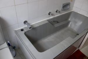 bañera blanca con grifo en el baño en Bougainvillea at Boskruin en Johannesburgo