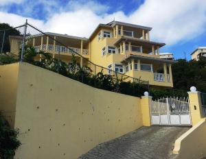 a yellow house with a white fence in front of it at South Sea House in Cap Estate