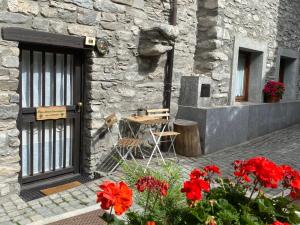 une table et des chaises devant un bâtiment en pierre avec des fleurs rouges dans l'établissement Casa dolce Courmayeur cir0009, à Courmayeur