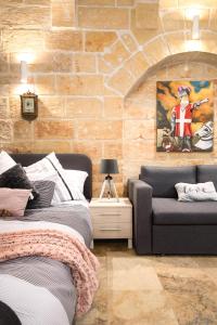 1 dormitorio con cama, sofá y pared de ladrillo en MCC Suites Valletta, en La Valeta