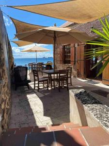 Barrel House Suite St Eustatius في أورانجستاد: فناء مع طاولة وكراسي ومظلات