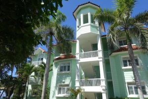 un edificio verde y blanco con palmeras delante en The Victorian Luxury Condo O-1, en Cabarete