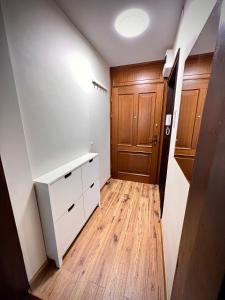 Habitación vacía con armario blanco y puerta de madera en Nocleg Opole Kopernik Apartament, en Opole