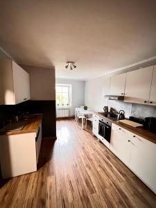 cocina con armarios blancos y suelo de madera en Nocleg Opole Kopernik Apartament, en Opole