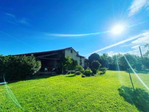 a house on a lawn with the sun in the sky at L'Apouticayre in Montaut