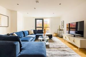 sala de estar con sofá azul y TV en The Clapham Dream - Captivating 3BDR with Garden & Parking, en Londres