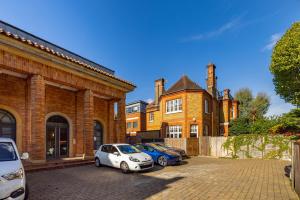 two cars parked in front of a brick building at The Clapham Dream - Captivating 3BDR with Garden & Parking in London
