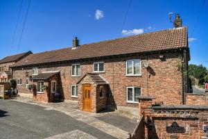 a brick house with a brown door on a street at Dovecote Farm House in Goole