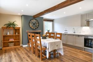 a kitchen with a table and chairs and a clock on the wall at Dovecote Farm House in Goole