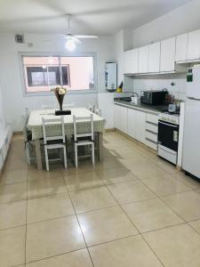 een keuken met een tafel en stoelen en een keuken met witte kasten bij Departamento luminoso y céntrico in Santiago del Estero