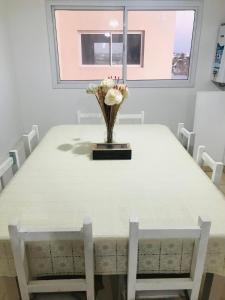 a dining room table with a vase of flowers on it at Departamento luminoso y céntrico in Santiago del Estero