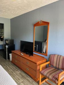 een hotelkamer met een televisie en een dressoir met een spiegel bij Deerfield Inn in Adamsville