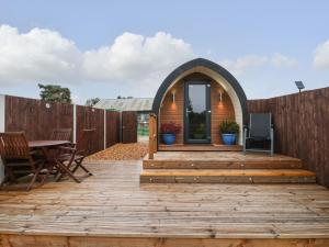 a wooden deck with a table and a fence at The Pod at Bank House Farm in Stafford