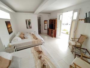 een witte slaapkamer met een bed en een stoel bij Casa Ego in Cartagena