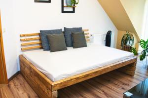 una camera da letto con letto in legno, lenzuola e cuscini bianchi di Apartment Bavaria - Zentral mit Stellplatz, Küche & Netflix a Pfaffenhofen an der Ilm
