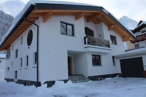 Una casa con nieve en el suelo delante de ella. en Alpin Juwel Apartments, en Galtür